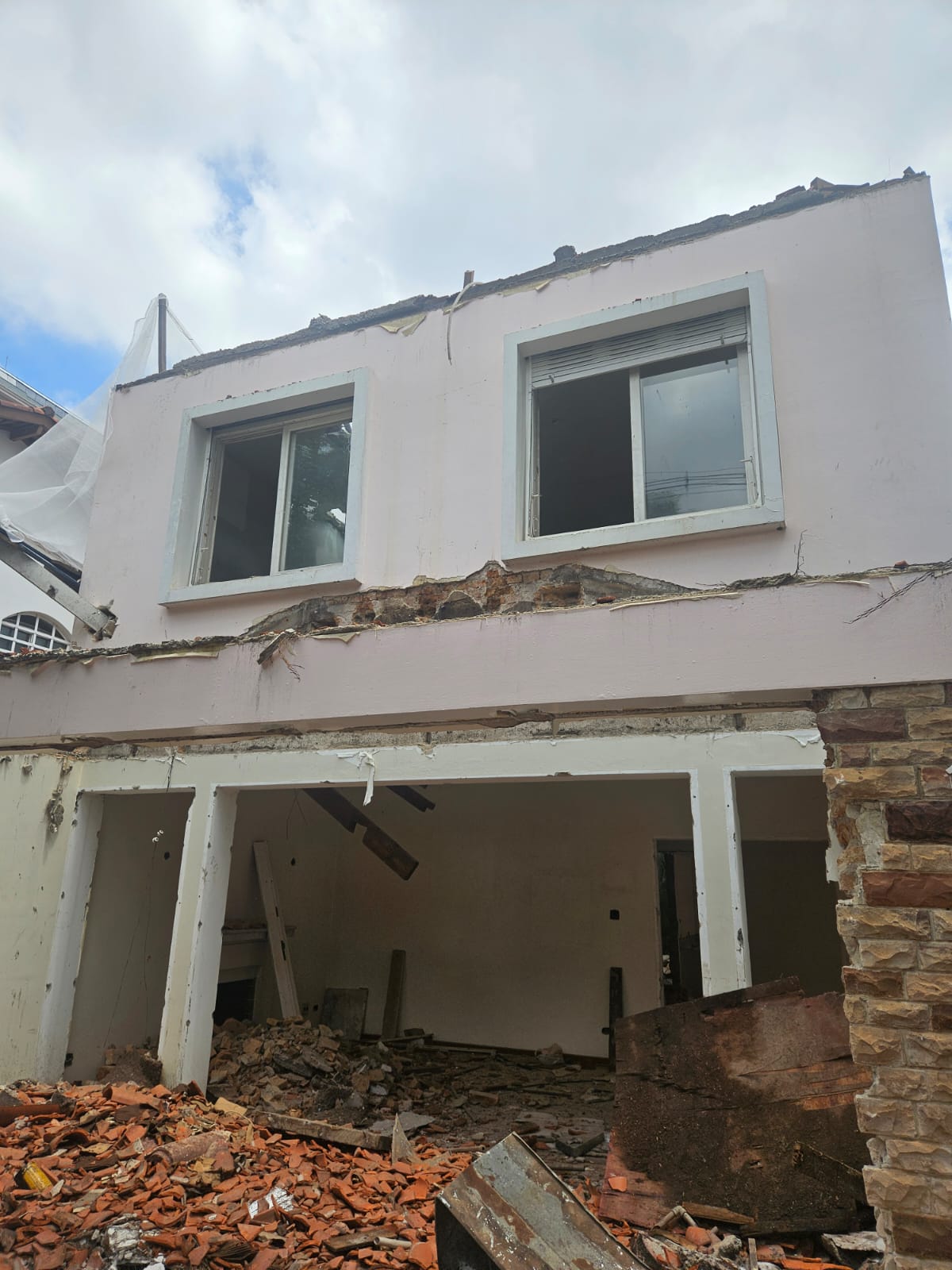 Casa em demolição com telhado removido e estrutura exposta